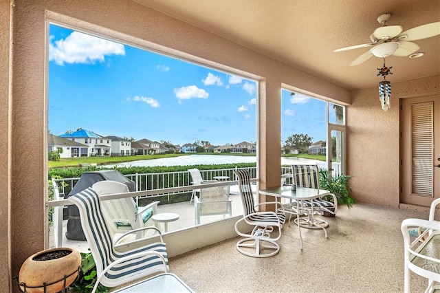 exterior space with ceiling fan, a water view, a balcony, and a residential view