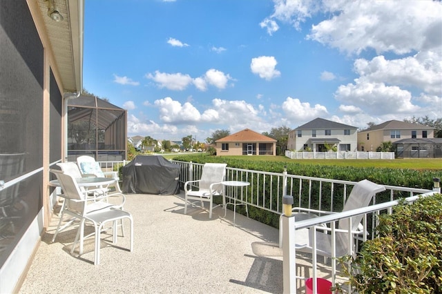 view of patio with a balcony, glass enclosure, a residential view, and area for grilling