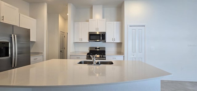 kitchen featuring stainless steel appliances, white cabinetry, sink, and a center island with sink