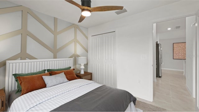 bedroom with light tile patterned flooring, stainless steel refrigerator, ceiling fan, and a closet