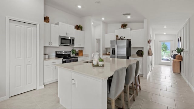 kitchen with white cabinetry, appliances with stainless steel finishes, and a kitchen island with sink