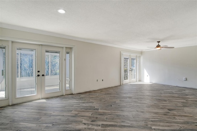 spare room featuring a textured ceiling, ornamental molding, dark wood-style flooring, and french doors