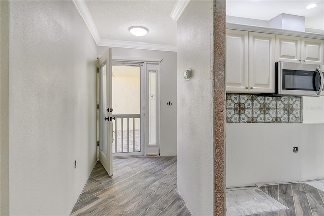 hall with a textured ceiling, a textured wall, ornamental molding, and wood tiled floor