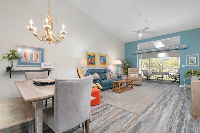 dining space with hardwood / wood-style flooring, ceiling fan with notable chandelier, and high vaulted ceiling