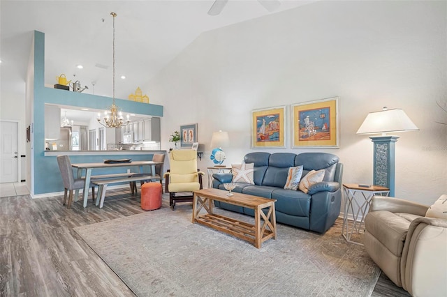 living room with ceiling fan with notable chandelier, hardwood / wood-style floors, and high vaulted ceiling