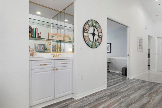 bar featuring white cabinets and light hardwood / wood-style flooring