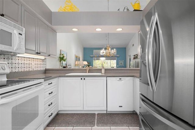 kitchen featuring sink, decorative light fixtures, kitchen peninsula, white appliances, and white cabinets