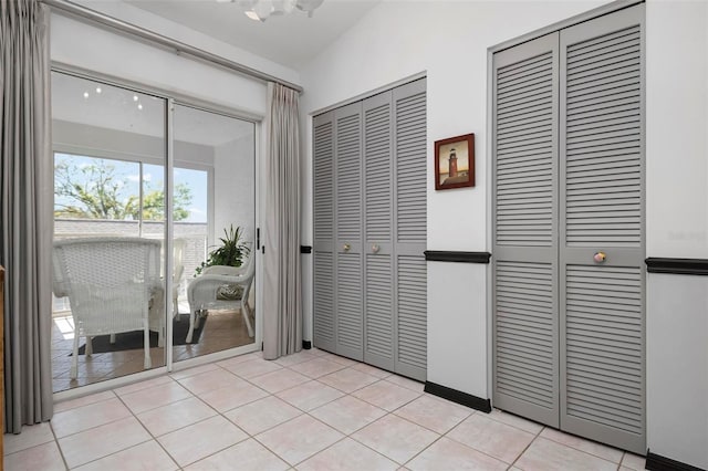 unfurnished bedroom with access to exterior, two closets, and light tile patterned floors