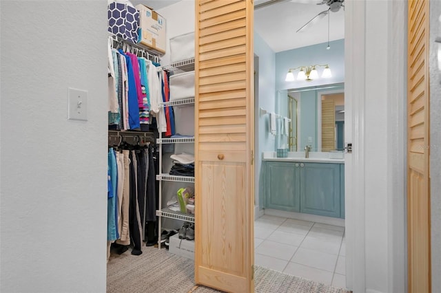 walk in closet featuring light tile patterned flooring, sink, and ceiling fan