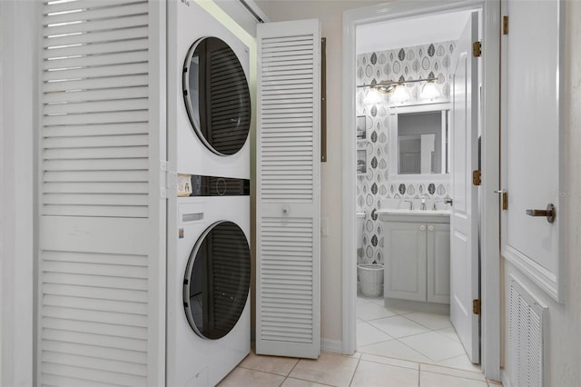 laundry area with stacked washer / dryer and light tile patterned floors