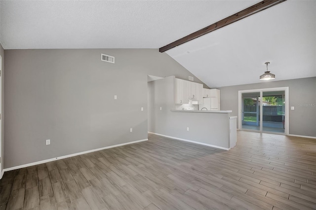 unfurnished living room featuring vaulted ceiling with beams, light hardwood / wood-style floors, and a textured ceiling