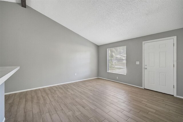 interior space featuring lofted ceiling, a textured ceiling, and light wood-type flooring