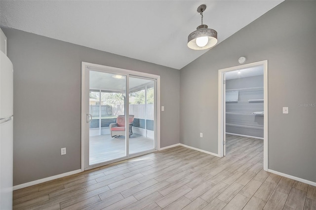 spare room with vaulted ceiling and light hardwood / wood-style floors