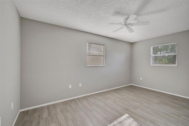 empty room featuring a textured ceiling, ceiling fan, and light wood-type flooring