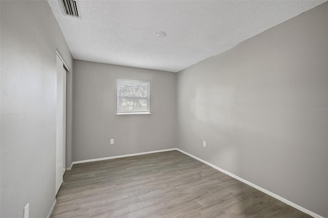 spare room with light hardwood / wood-style flooring and a textured ceiling