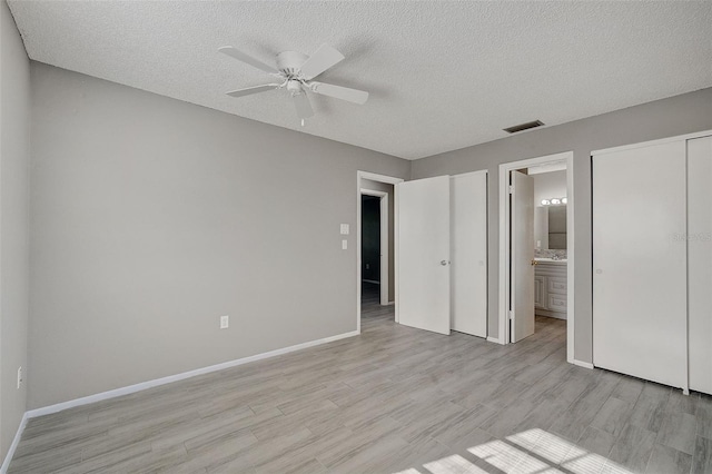 unfurnished bedroom with ceiling fan, ensuite bath, light hardwood / wood-style floors, and a textured ceiling