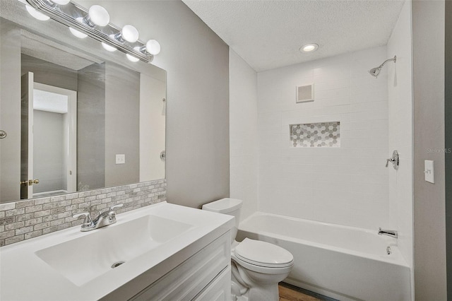 full bathroom with toilet, tasteful backsplash, a textured ceiling, vanity, and tiled shower / bath combo