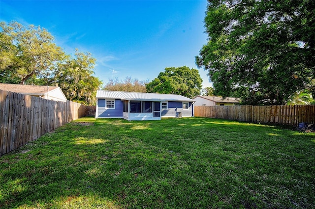 rear view of house with a lawn and a sunroom