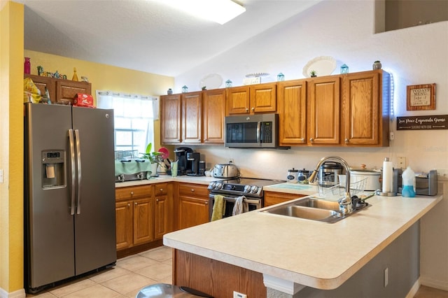 kitchen with sink, vaulted ceiling, kitchen peninsula, and appliances with stainless steel finishes