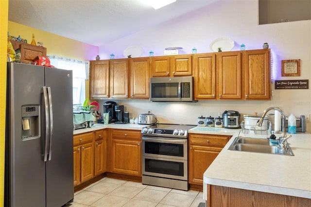 kitchen featuring stainless steel appliances, vaulted ceiling, sink, and light tile patterned flooring