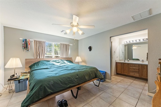 bedroom with light tile patterned flooring, ensuite bath, and ceiling fan