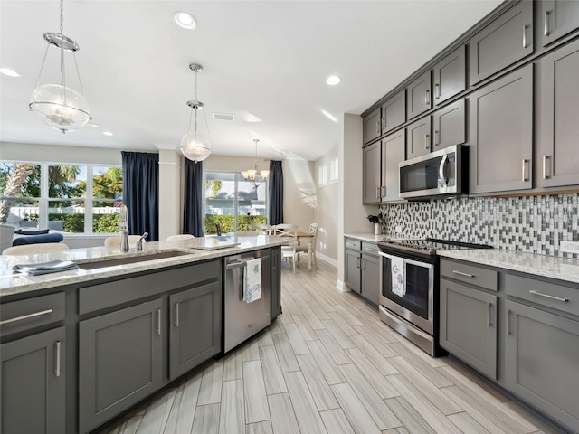 kitchen with sink, decorative light fixtures, gray cabinets, and appliances with stainless steel finishes