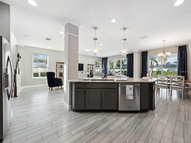 kitchen featuring decorative columns, sink, hanging light fixtures, light stone counters, and stainless steel appliances