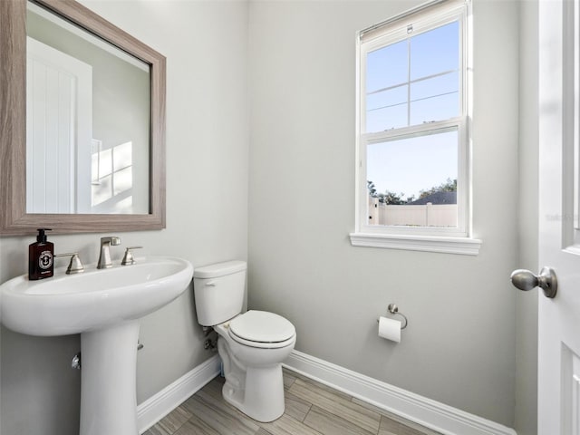 bathroom with wood-type flooring, toilet, and sink