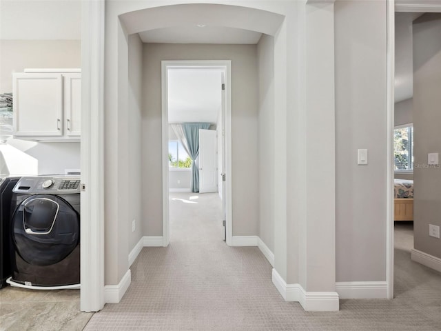 laundry room featuring washer / clothes dryer, plenty of natural light, light colored carpet, and cabinets