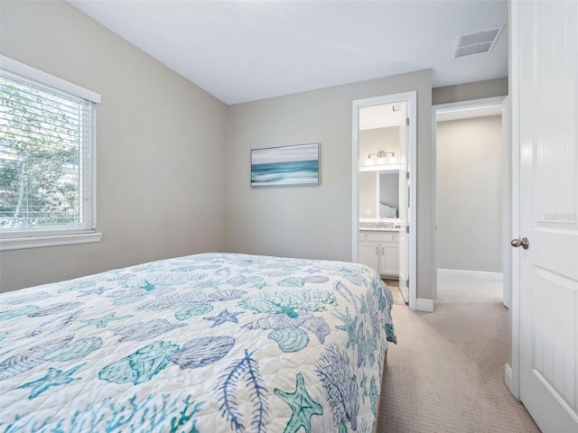 bedroom with connected bathroom and light carpet