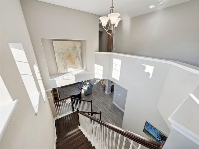 staircase featuring hardwood / wood-style flooring, a towering ceiling, and a notable chandelier