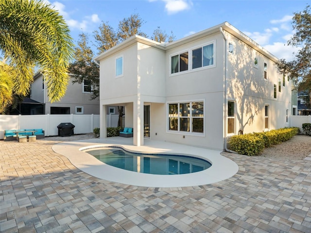 back of house featuring outdoor lounge area, a fenced in pool, and a patio area