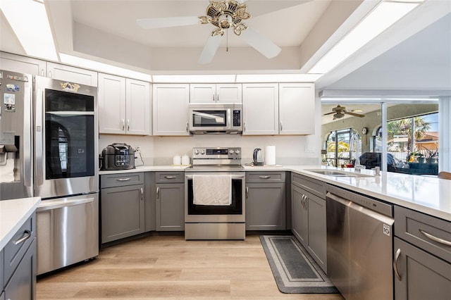 kitchen with sink, gray cabinetry, white cabinets, light hardwood / wood-style floors, and stainless steel appliances