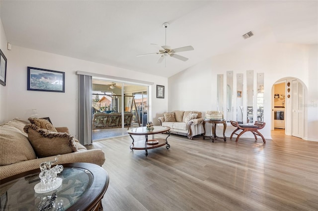 living room featuring ceiling fan, lofted ceiling, washer / dryer, and light hardwood / wood-style floors