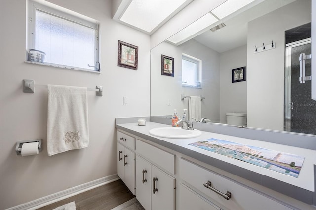 bathroom featuring hardwood / wood-style flooring, vanity, toilet, and a shower with shower door