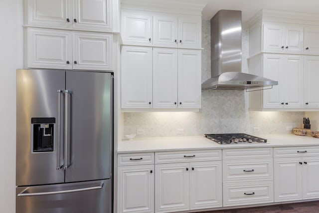 kitchen featuring stainless steel appliances, white cabinetry, tasteful backsplash, and wall chimney exhaust hood