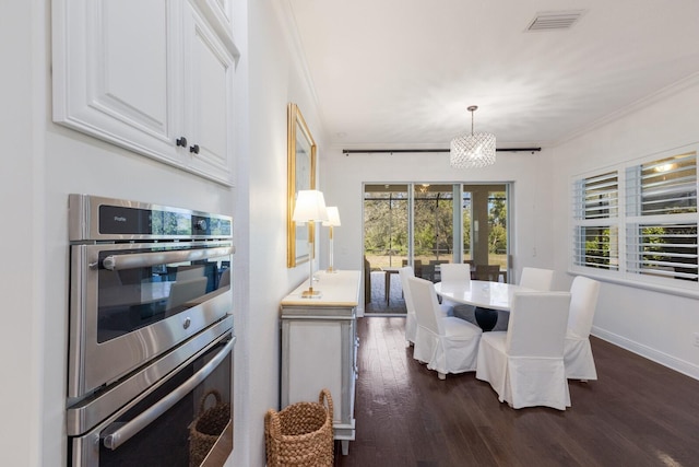 dining room with a notable chandelier, crown molding, and dark wood-type flooring