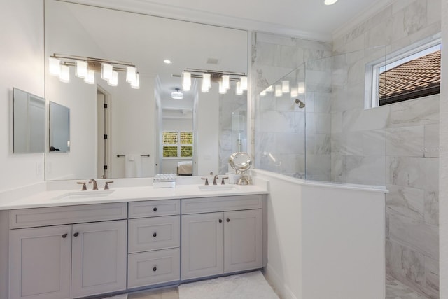 bathroom featuring a tile shower, vanity, and crown molding