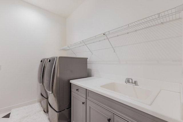 clothes washing area featuring cabinets, sink, and independent washer and dryer