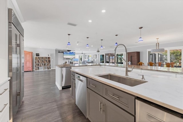 kitchen with pendant lighting, stainless steel appliances, light stone countertops, and sink