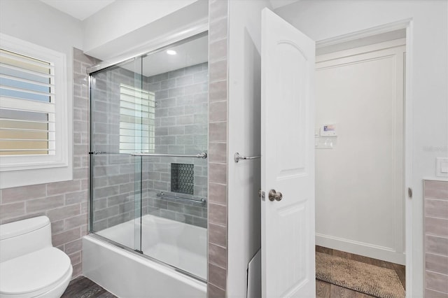 bathroom with toilet and combined bath / shower with glass door