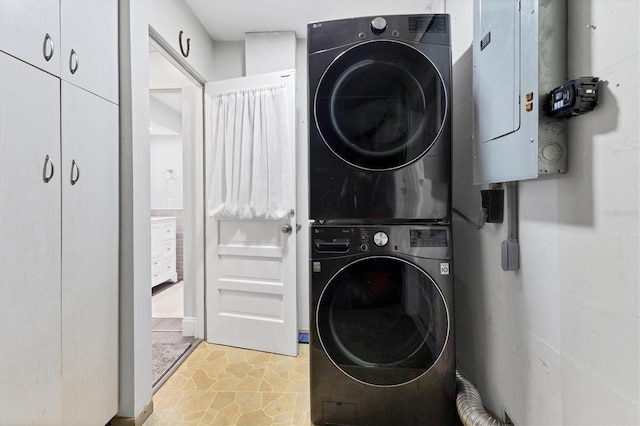 clothes washing area with stacked washer and dryer and electric panel