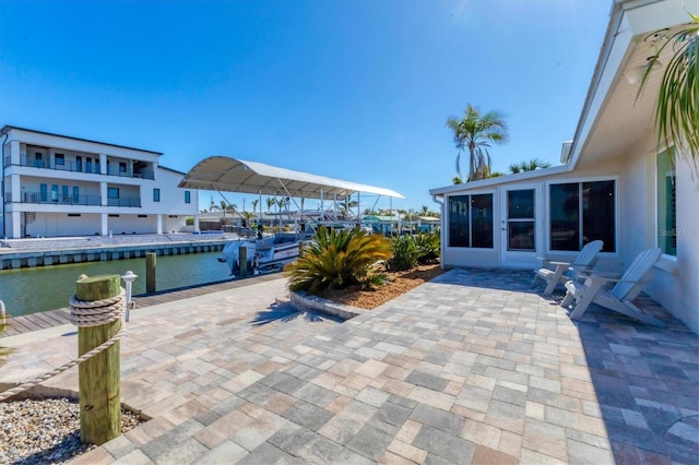 view of patio featuring a dock, a sunroom, and a water view