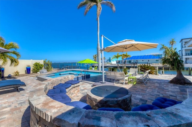 view of pool with a patio, a water view, and an in ground hot tub