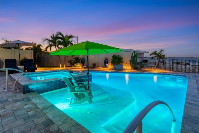 pool at dusk with an in ground hot tub