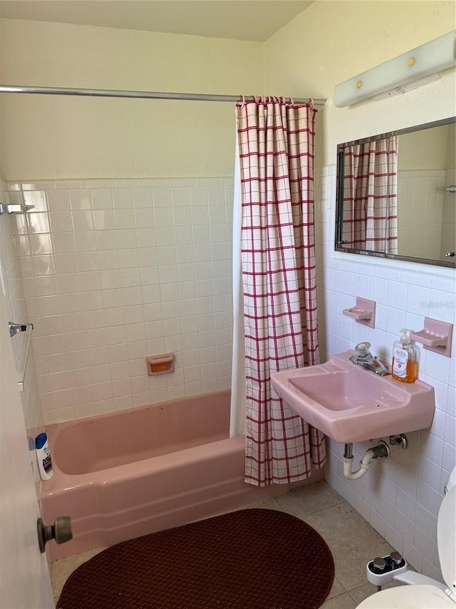 full bathroom featuring toilet, sink, tile walls, shower / bath combo with shower curtain, and tile patterned flooring