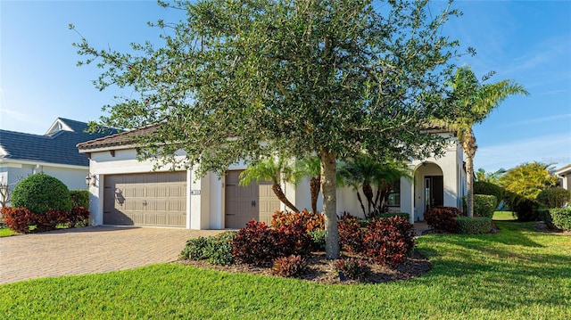 view of front of property with stucco siding, a front lawn, decorative driveway, and a garage