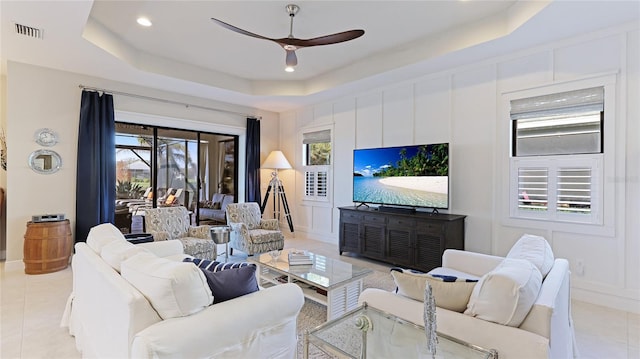 tiled living room featuring a raised ceiling and ceiling fan