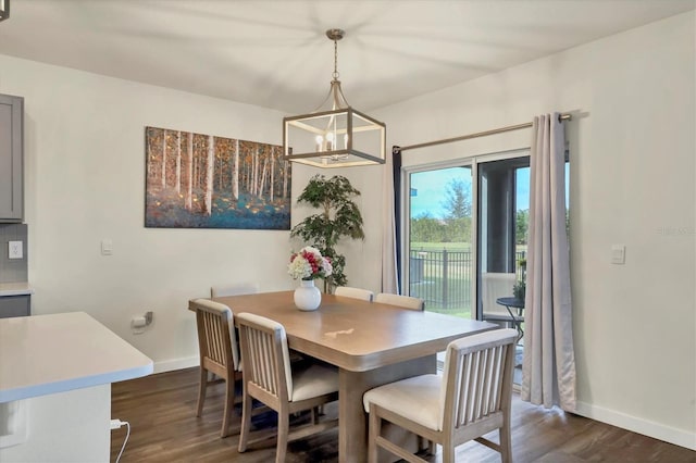 dining area with dark wood-type flooring and a notable chandelier