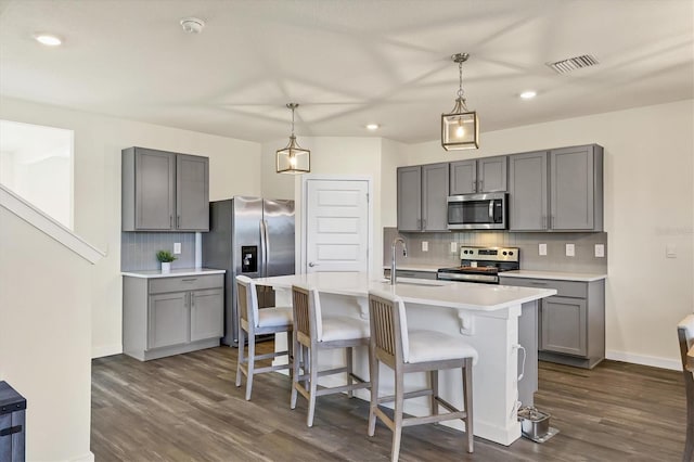 kitchen with stainless steel appliances, sink, an island with sink, and hanging light fixtures